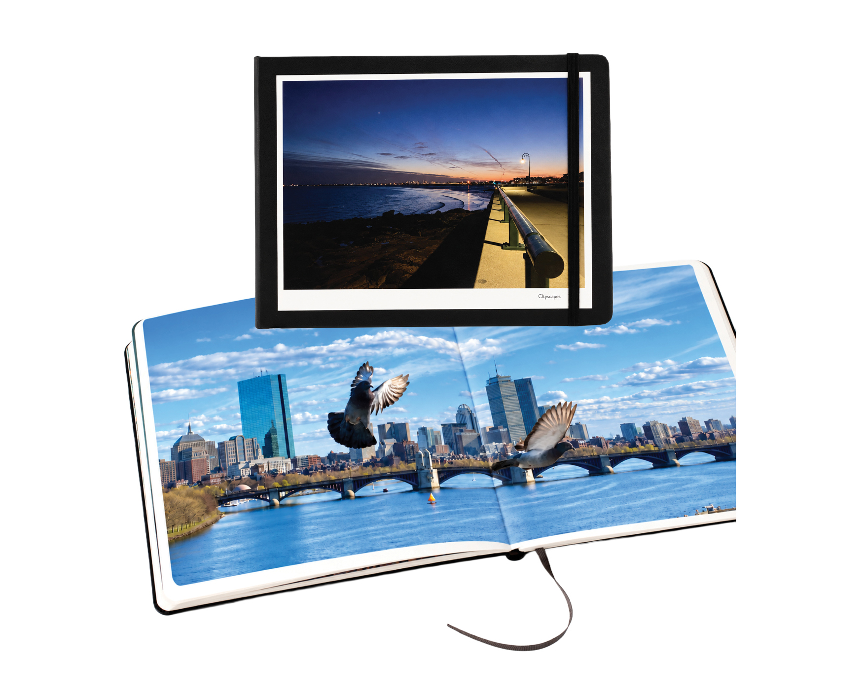 Closed black Moleskine photo book with an elastic closure, above an open photo book showing a cityscape spread